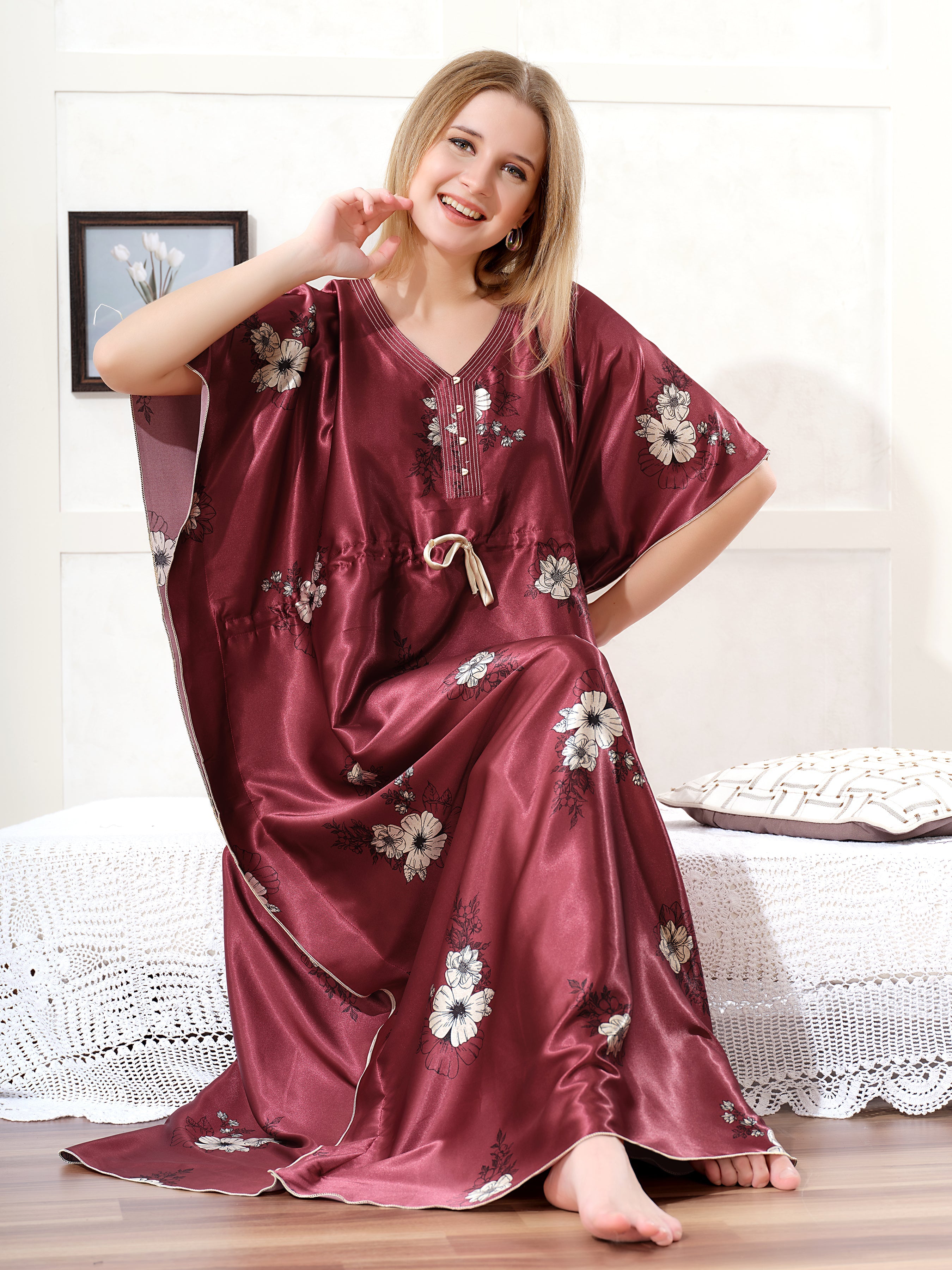 Model sitting wearing maroon satin kaftan for women with cream floral print and drawstring waist